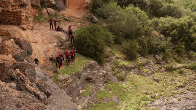 Canyoning group walking in single file to abseiling spot