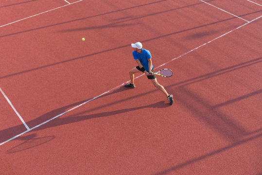 Male tennis player hitting the ball with backhand technique