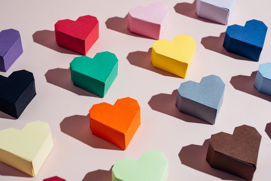 Multi colored paper hearts on a pink background