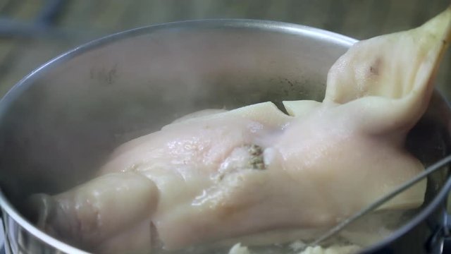 Half pigs head being boiled for brawn