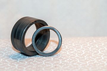 His and hers wedding bands made from Damascus steel against a bokeh background.