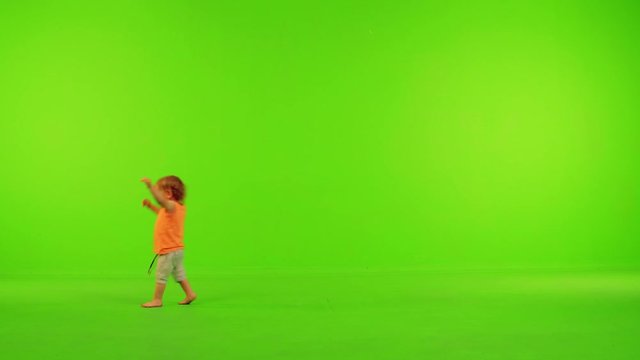 Cute little toddler runs happily from side to side in a full shot over a green screen.