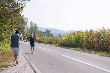 videographer recording while couple jogging along a country road