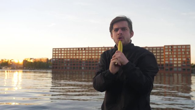 Slow motion video of a man pretending to shoot a banana like a gun and holstering it