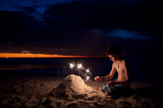 Boy at the beach at night with sparklers