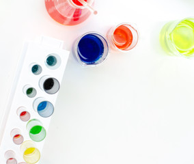 top view of laboratory equipments. A blue liquid watch glass, flask, test tubes and beaker on the white table