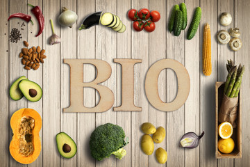 Wort BIO und verschiedene Gemüse auf Holzhintergrund