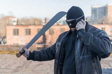 bandit with a machete in a black mask talking on the phone