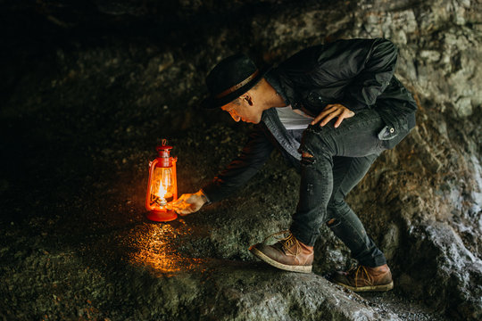 Man Lighting Lantern In Cave