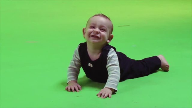 A small baby laughs over a green screen.