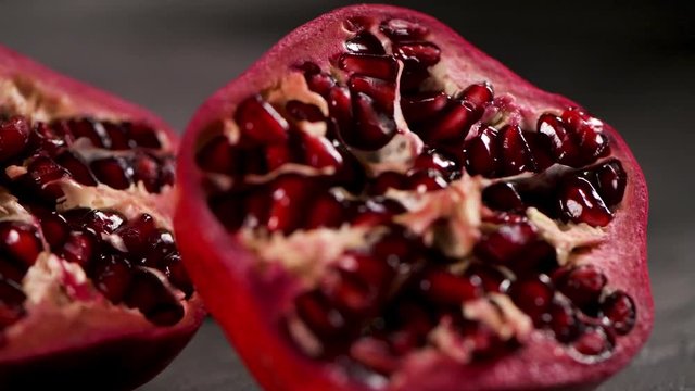 Ripe pomegranate fruit and pomegranate seeds on dark background, close-up. Healthy vegetarian antioxidant organic diet food