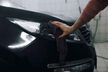 Car detailing - the man holds the microfiber in hand and polishes the car. Selective focus