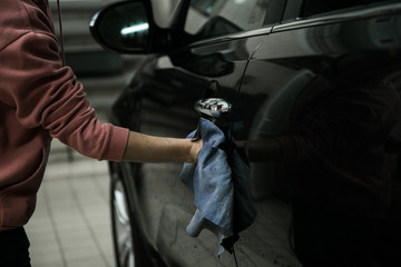 Fototapeta na wymiar Car detailing - the man holds the microfiber in hand and polishes the car. Selective focus
