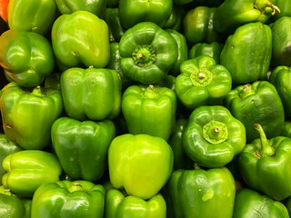 Obraz na płótnie Canvas Green bell peppers on a counter in the supermarket. A large number of green peppers in a pile. Farmer market