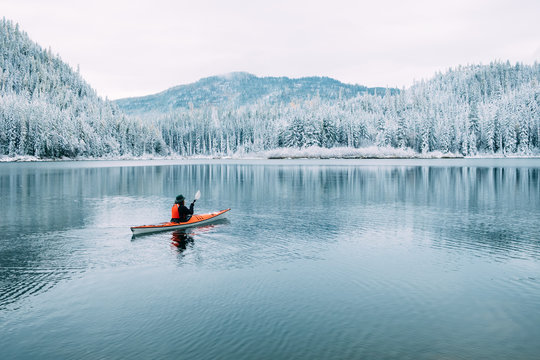 A lone sea kayaker paddles on a lake in a winter landscape in Montana