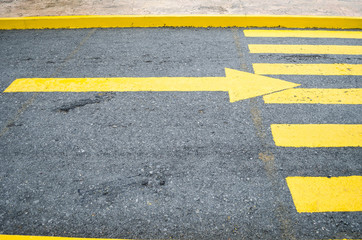 close up to a yellow arrow in the direction to the right, yellow pedestrian crossing with an arrow