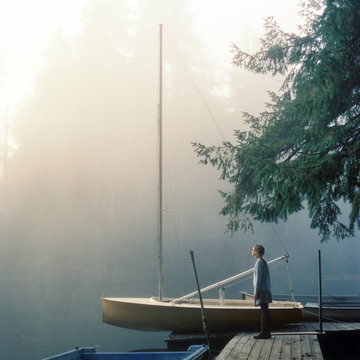 Twelve year old girl stands on a dock on a foggy morning on Fletcher Bay