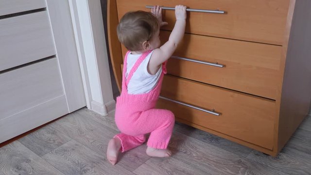 Little baby opens boxes of locker with things.