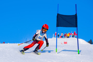 Young boy skiing in mountains. Active  kid with safety helmet, goggles and poles. Ski race for young children