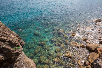Swimming in the crystal clear water and rocks at Monterosso al Mare on the Ligurian coast in Italy