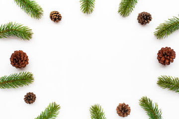 Christmas green framework with fir branches and pine cones on white background. Top view