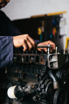 Mechanic fixing an engine for a head gasket repair in a garage.