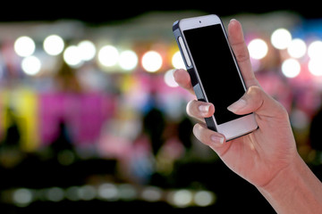 Man using a blank screen smartphone and blurry colorful bokeh background with clipping path on screen panel