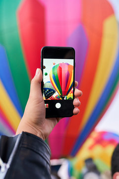 Person taking photo of a hot air balloon with cell phone