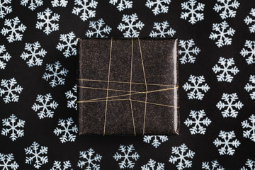 Gift wrapped in black on black background with snow stamps