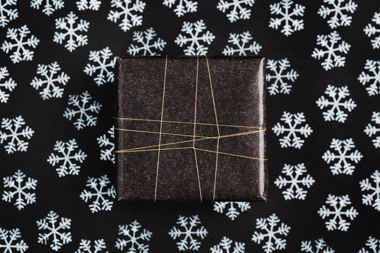 Gift wrapped in black on black background with snow stamps
