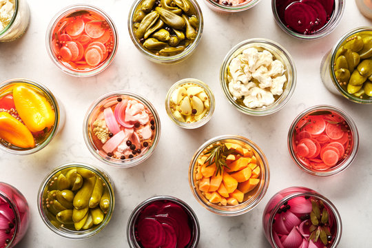 Colorful pickled vegetables on white marble background.