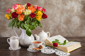 Still life roses, tea and a book on the table