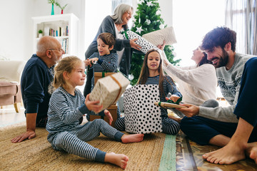 Family opening gifts for Christmas. Family wearing pajama celebrating Christmas at home.