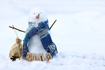 winter holidays 2019 cheerful snowman in a scarf with a gift on the background of snowdrifts