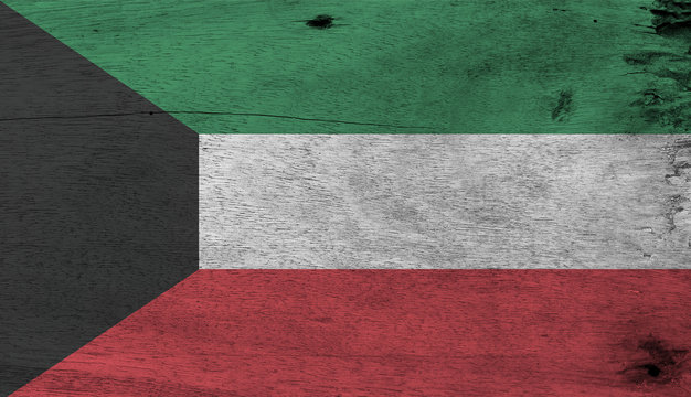 Flag of Kuwait on wooden plate background. Grunge Kuwaiti flag texture, green white and red color with black trapezium based on the hoist side.