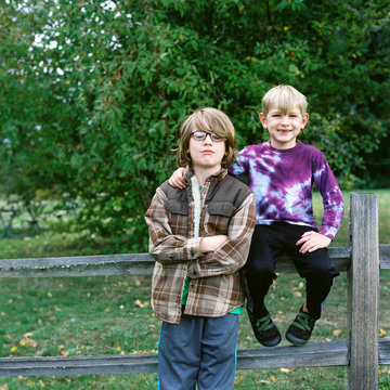 Two brothers pose on a split rail fence at on apple orchard
