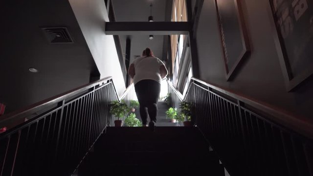 Back View Of Overweight Young Woman Walking Up The Stairs In The Cafe. Shot In 4k Resolution