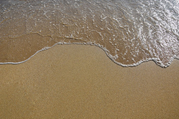 Fototapeta na wymiar Wave of blue sea on sandy beach. Abstract summer background