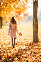 Season and people concept - beautiful happy young woman having fun with leaves in autumn park. Girl walking, resting outdoors