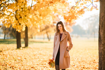Season and people concept - beautiful happy young woman having fun with leaves in autumn park. Girl...