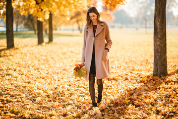 Season and people concept - beautiful happy young woman having fun with leaves in autumn park. Girl...