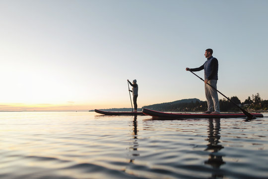 Couple stand up paddle boarding together at sunrise