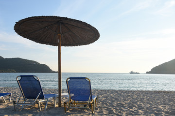 Two chairs and umbrella on sandy beach  in Greece. Summer beach with parasol