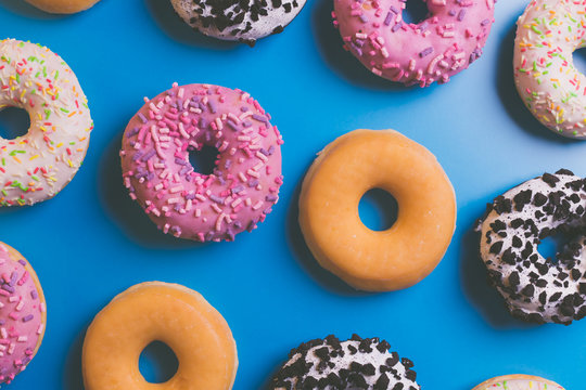 Top view of many colorful donuts on blue background.