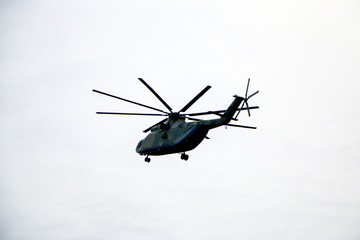 a large military helicopter hovers in the sky. A camouflaged helicopter flies at high speed.