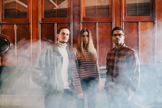 Portrait of young travelers standing in front of old wooden train.