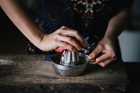Woman squeezing fresh pomegranate halve