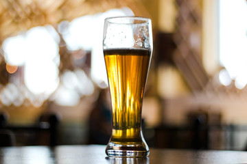 Glass of light beer on a dark pub.