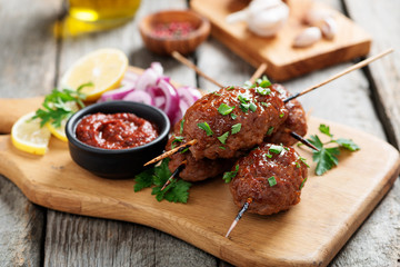 Tasty kebab with vegetables on a plate and sauce on the table. 