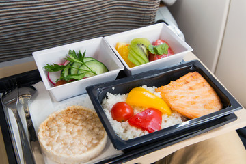 Food served in a passenger aircraft. In flight meal on the tray. Salad, butter and bread, fruits....